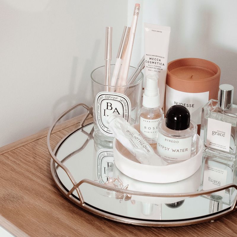 Makeup and beauty products on a mirrored vanity tray